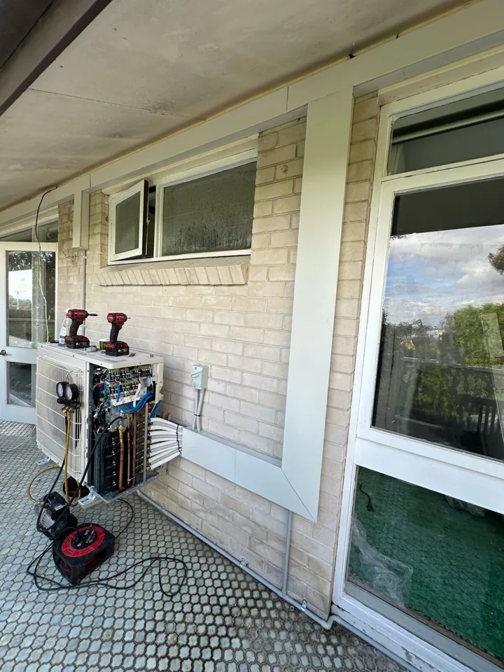 Multi-head outdoor air conditioning unit during pipework installation and commissioning, with connected refrigerant lines and commissioning equipment