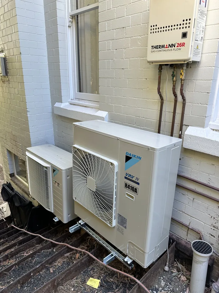 Daikin outdoor air conditioning units mounted beside the windows of a brick home